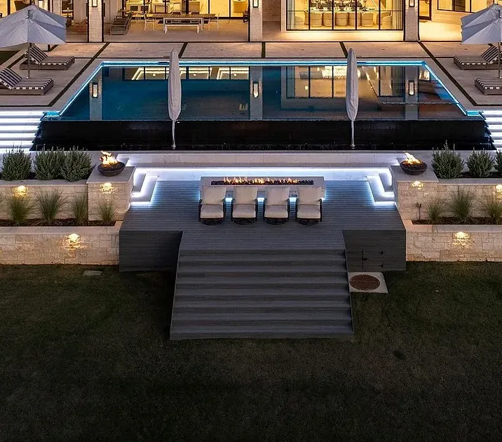 Terraced landscape with LED-lit planters, fire bowls, and infinity pool at a Kingdom Development estate